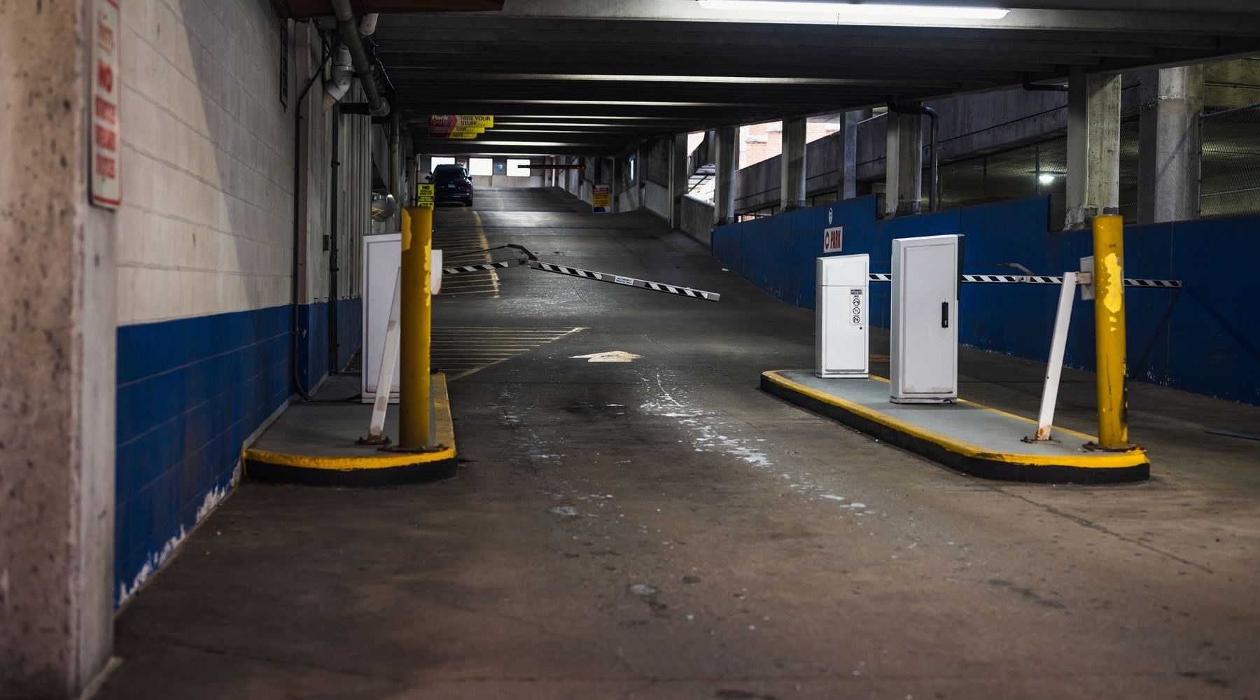 De oprit van een parkeergarage bij weinig licht, met slagbomen aan het eind.